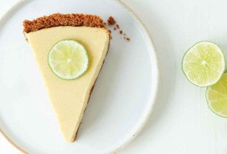 A slice of Classic Key Lime Pie with a graham cracker crust and sliced lime on top