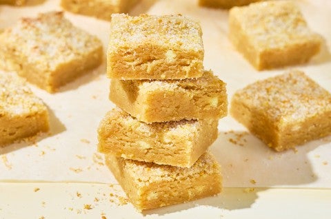 Stacked Alex Roberts Lemon Citrus Blondies on a countertop. - select to zoom