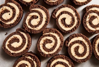 Sliced pinwheels of chocolate cake filled with Cookie Butter Whipped Ganache all laying side by side on a sheet tray.