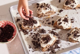 Glazed Cookies-and-Cream Scones being topped with cookie crumbles