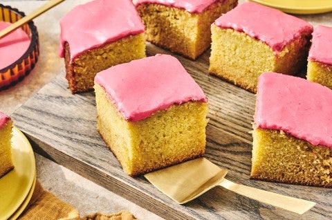 Cranberry-Orange Olive Oil Cake sliced up and arranged on a glass plate with a gold hued serving spatula under one of the golden slices. - select to zoom