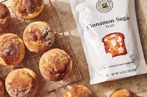 Cinnamon-Sugar Doughnut Muffins on a cooling rack with bag of cinnamon sugar - select to zoom