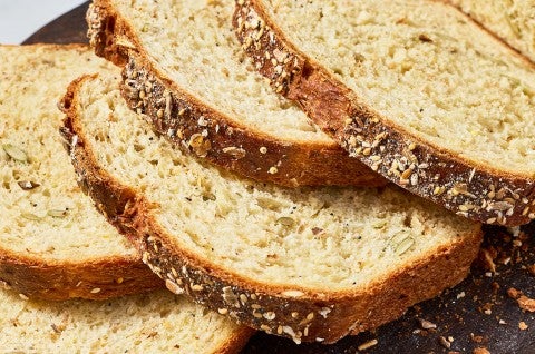Slices of Multigrain Protein Bread arranged on top of each other showing the crust and golden interior. - select to zoom