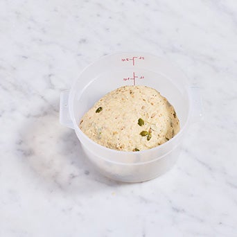 Multi-grain protein bread dough in a dough rising bucket.
