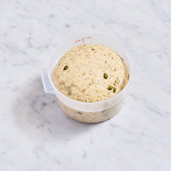 Multi-grain protein bread dough in a dough rising bucket after doubling in size.
