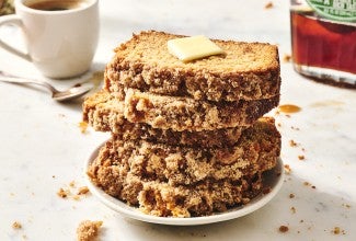 Five slices of Pancake Bread stacked on a plate showing a crumbly exterior and topped with butter.