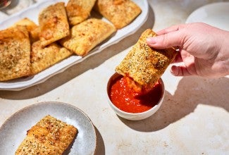 A Homemade Pizza Pocket being dipped in marinara sauce