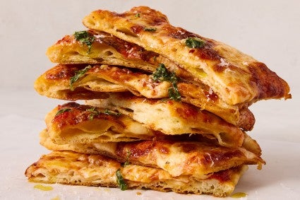 A stack of flaky puff crust pizza slices showing the crispy and flaky layers of dough and toppings - seen from a side angle.