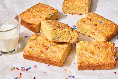 Small-Batch Birthday Cake Blondies on a counter with a glass of milk