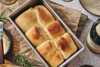 A loaf pan filled with freshly baked Small-Batch Parker House Rolls.