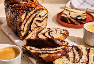 Chocolate Sourdough Babka sliced and arranged on a table with coffee and other plates.